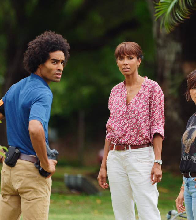 "Deadly Tropics - Mord aus Liebe": Aurélien (Julien Béramis), Mélissa (Sonia Rolland) und Gaëlle (Béatrice de la Boulave) stehen vor einem Krankenwagen und blicken besorgt in dieselbe Richtung.