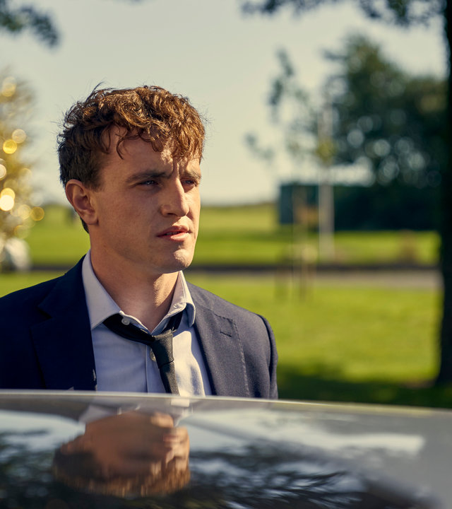 "Normal People - Depression": Connell (Paul Mescal) steht im Anzug neben einem schwarzen Auto und schaut traurig in die Ferne.