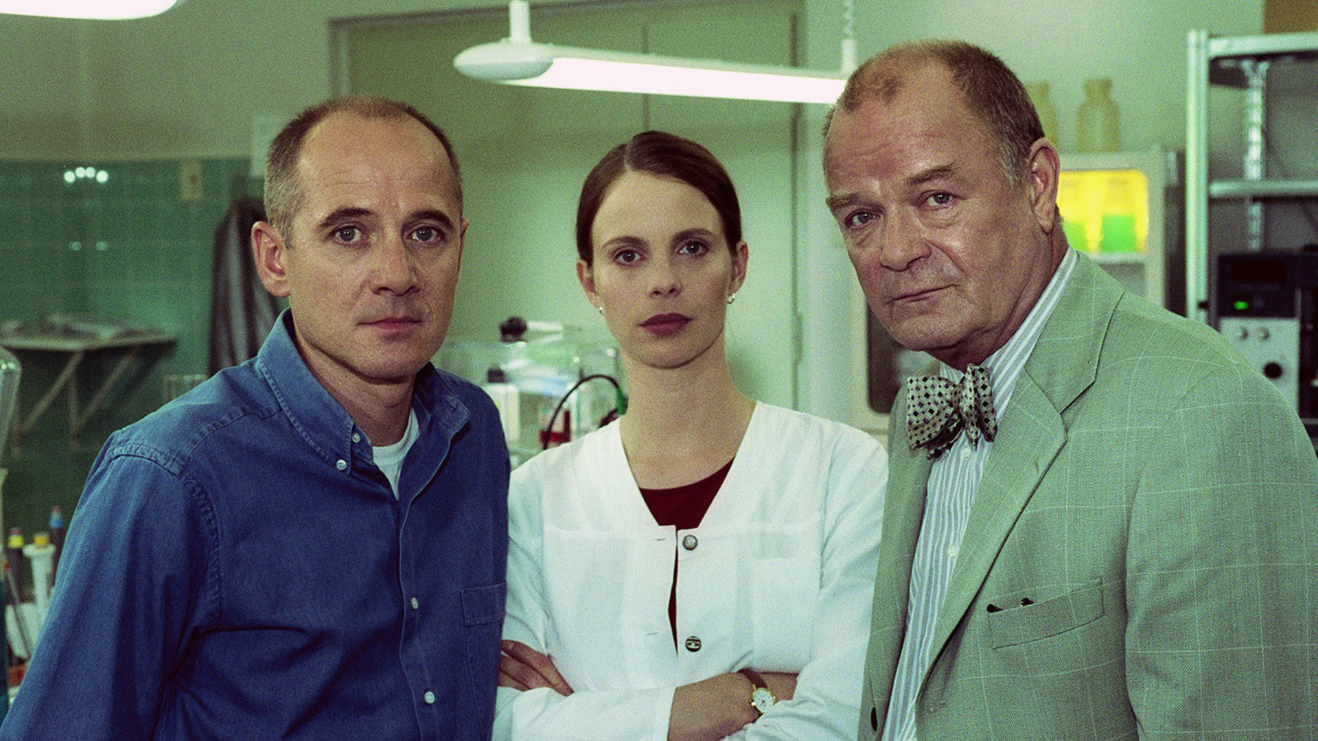 "Der letzte Zeuge - Der Tag, an dem ein Vogel vom Himmel fiel": Dr. Kolmaar (Ulrich Mühe), Prof. Bondzio (Dieter Mann) und Dr. Leilah Berg (Julia Jäger) stehen im Labor und blicken in die Kamera.