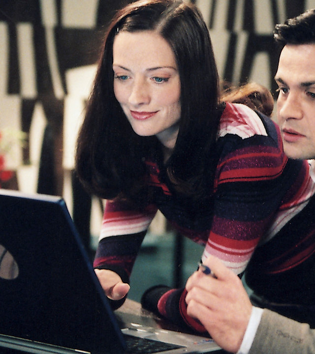 "Bianca - Wege zum Glück: Kapitel 135": An einem Schreibtisch: Pascal (Michael Rotschopf) und Katy (Nicola Ransom) schauen in einen geöffneten Laptop. Katy lächelt und Pascal wirkt angespannt.