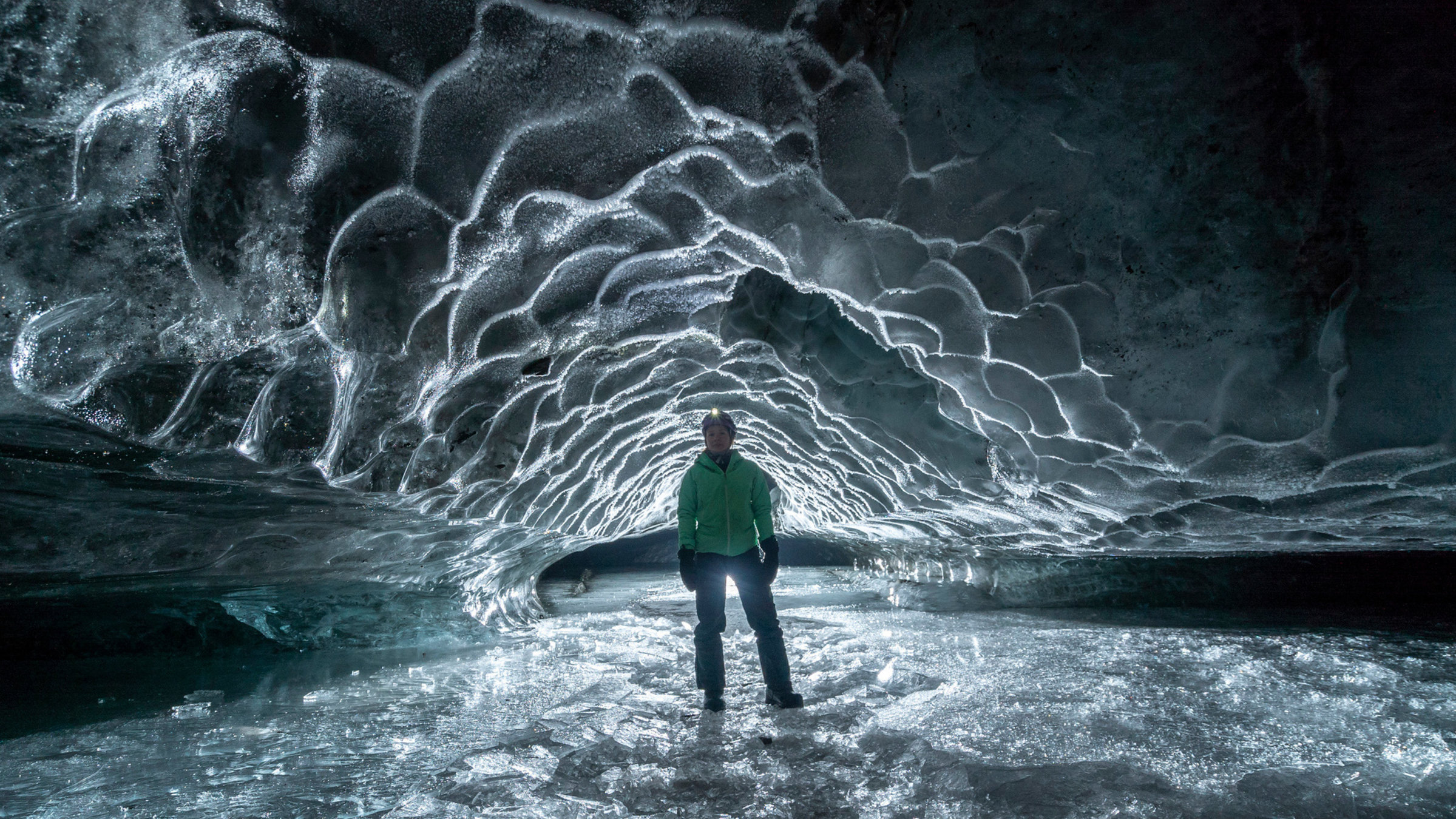 "Terra X: Faszination Wasser - Singende Wale und das Geheimnis der Regentropfen": Eine Eishöhle, geheimnisvoll ausgeleuchtet. In der Mitte steht ein Forscher mit Stirnlampe.