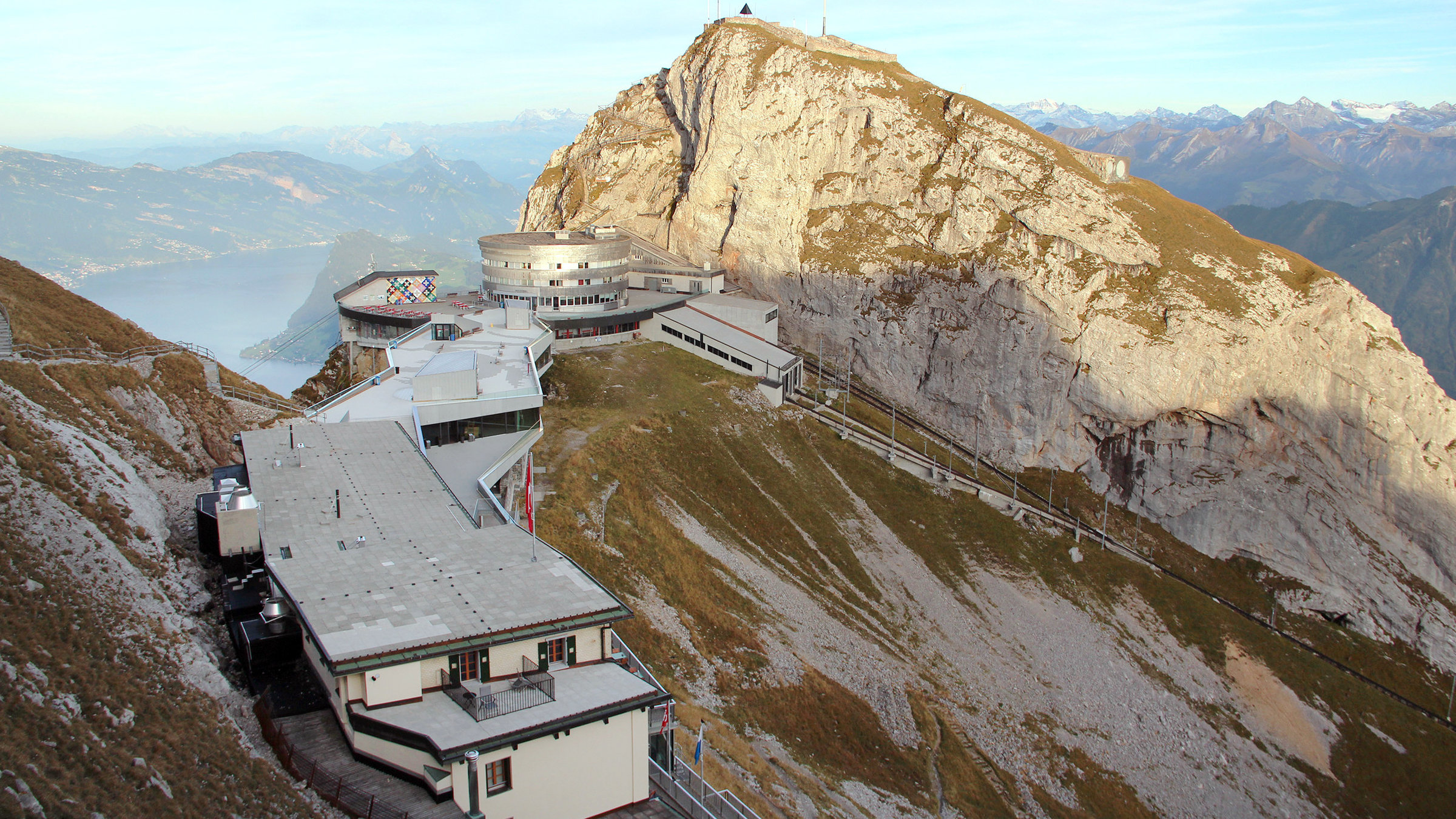 "Höhenrausch - Alpenländische Bahnraritäten": Blick auf das Kulm-Hotel mit Terrasse, Luftseilbahn-Station, Zahnradbahn, Bergstation und Sonnenpyramide.