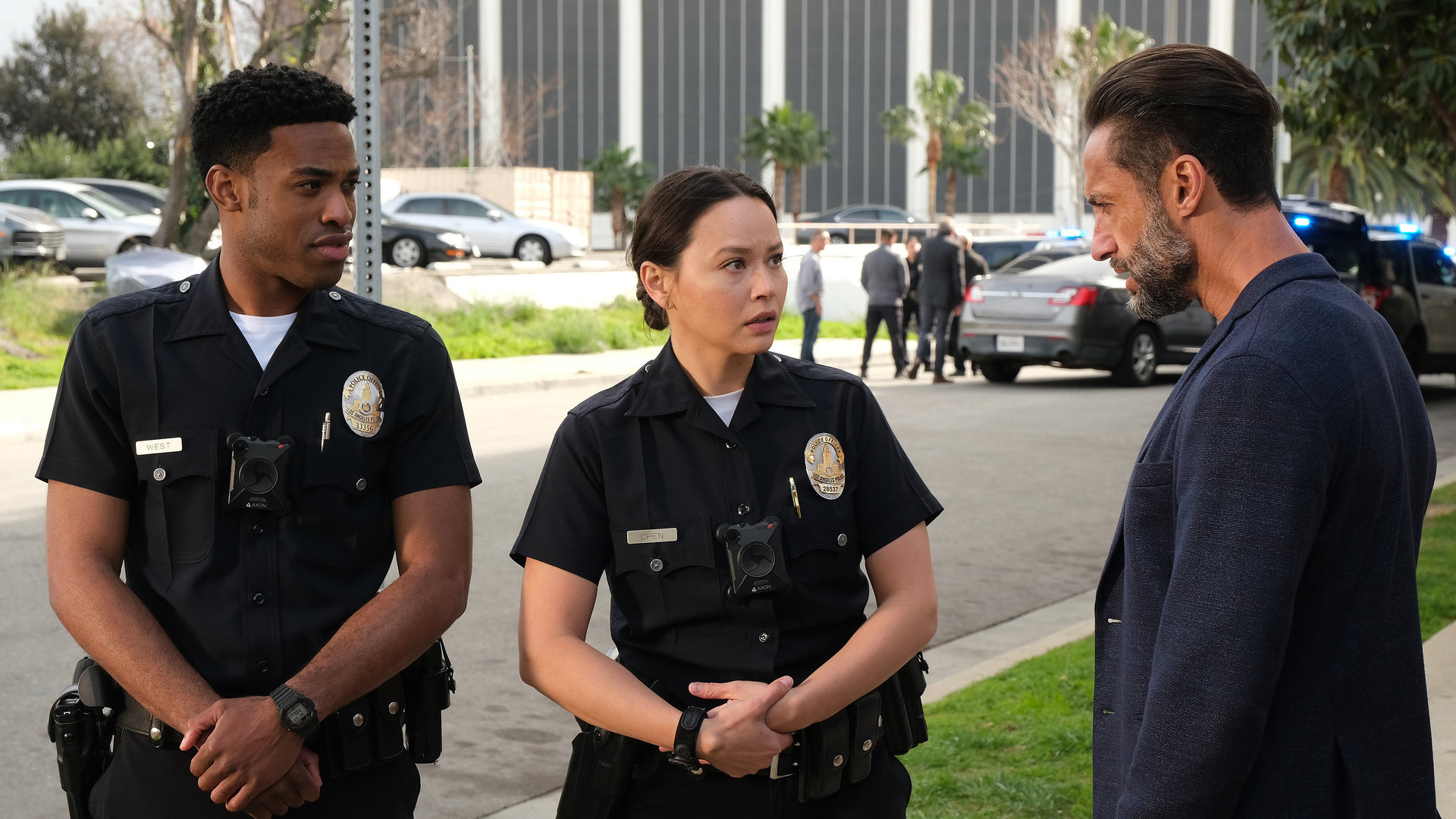 "The Rookie - Licht und Schatten": Chen (Melissa O´Neil) und West (Titus Makin Jr.) stehen mit verschränkten Armen neben Detective Caradine (Kamar de los Reyes) am Straßenrand und schauen ihn aufmerksam an.