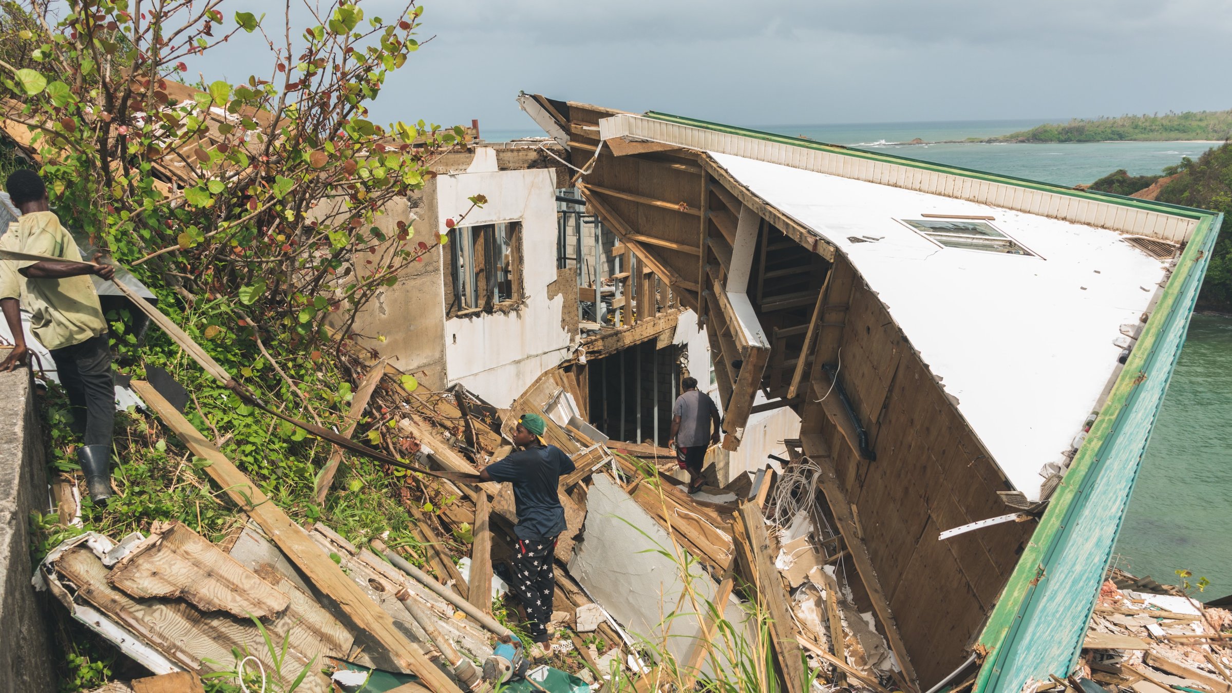 "planet e.: Karibische Sturmfront - Wie der Inselstaat Dominica dem Klimawandel trotzt": Mann in den Trümmern eines Hauses nach dem Hurrikan an einer Küste.