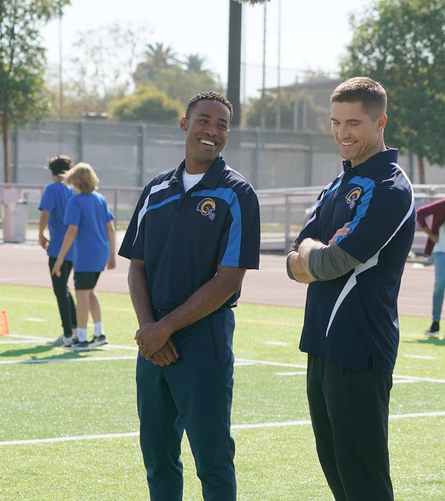 "The Rookie - Sicher ist sicher": Tim Bradford (Eric Winter) und Jackson West (Titus Making Jr.) stehen, sich amüsierend, zwischen dem Trainer und einem Jungen aus der Mannschaft.