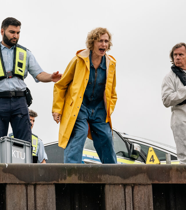 "SOKO Köln - Männerfrühstück": Deborah Brügge (Friederike Wagner) steht schreiend auf einer Plattform. Links neben ihr steht ein Mann mit einer Sicherheitsweste, der sie am Arm festhält.