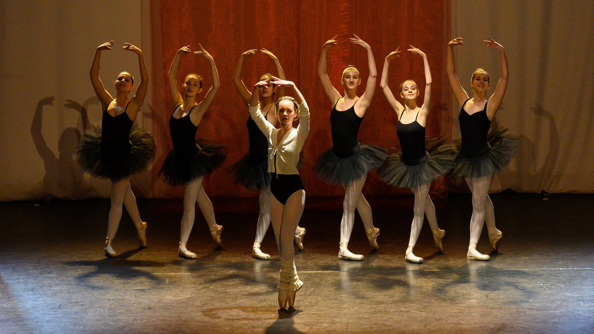 "SOKO Stuttgart - Der letzte Tanz“: Viven Schleicher (Barbara Prakopenka) tanzt ein Ballettsolo auf der Bühne. Hinter ihr tanzen sechs weitere Mädchen (Komparsen), die allesamt mit schwarzen Tutus bekleidet sind. Am Rand der Bühne steht die Tanzlehrerin (Karolina Buchta), die den Tänzerinnen Einsätze und Hilfestellungen gibt.