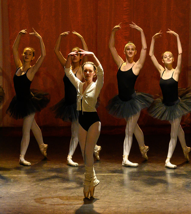"SOKO Stuttgart - Der letzte Tanz“: Viven Schleicher (Barbara Prakopenka) tanzt ein Ballettsolo auf der Bühne. Hinter ihr tanzen sechs weitere Mädchen (Komparsen), die allesamt mit schwarzen Tutus bekleidet sind. Am Rand der Bühne steht die Tanzlehrerin (Karolina Buchta), die den Tänzerinnen Einsätze und Hilfestellungen gibt.
