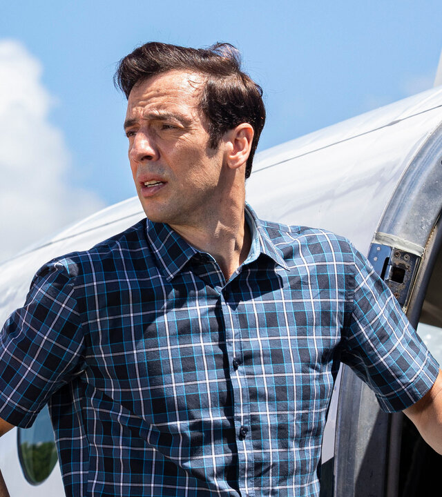 "Death in Paradise - Saint Auguste": DI Neville Parker (Ralf Little) steht nachdenklich vor einer Flugzeugtür und blickt seitlich in die Ferne.