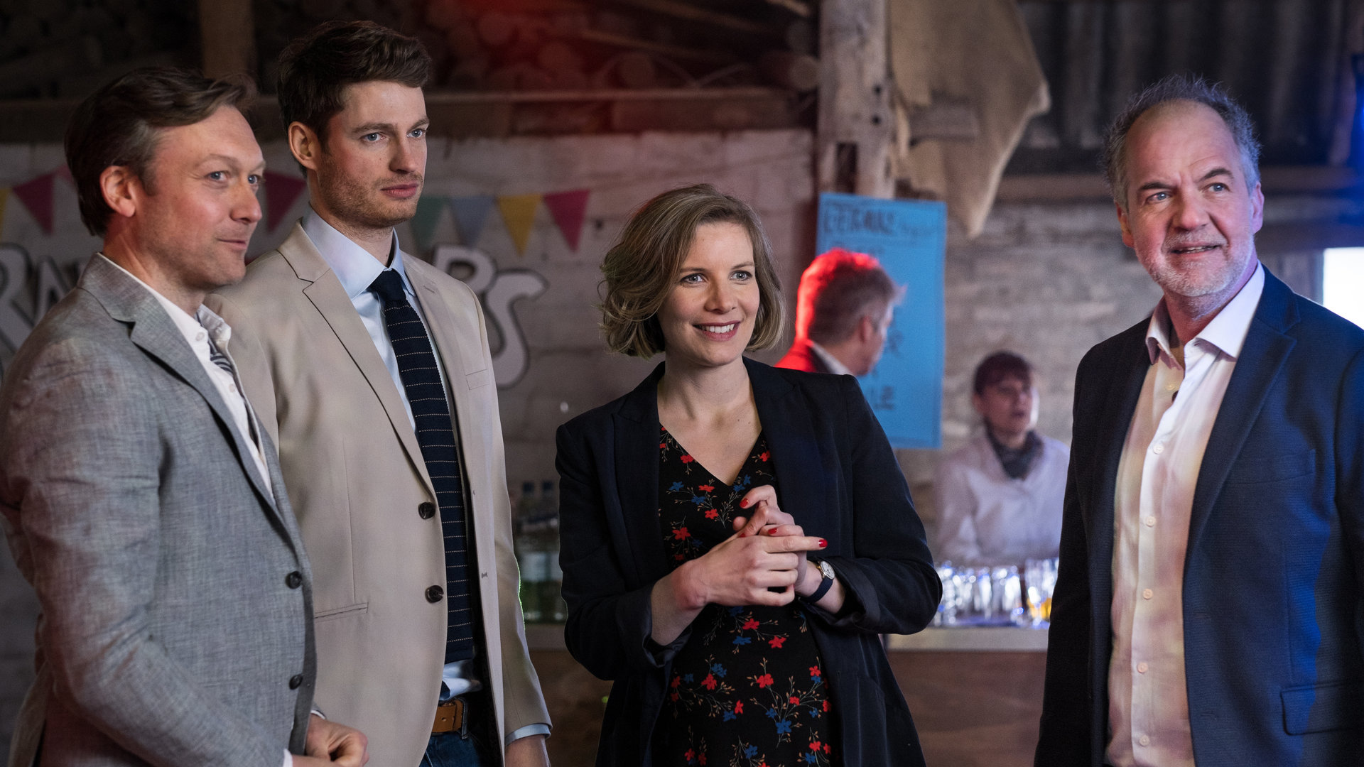 "SOKO Hamburg - Tödliche Hochzeit": Lena Testorp (Anna von Haebler) und Oskar Schütz (Marek Erhardt) stehen mit Lars Tretschok (Robin Sondermann) und Raffi von Kropp (Jonas Anders) in einer dekorierten Scheune. Lena und Oskar blicken lachend nach vorne. Das Hochzeitspaar sieht in die gleiche Richtung.