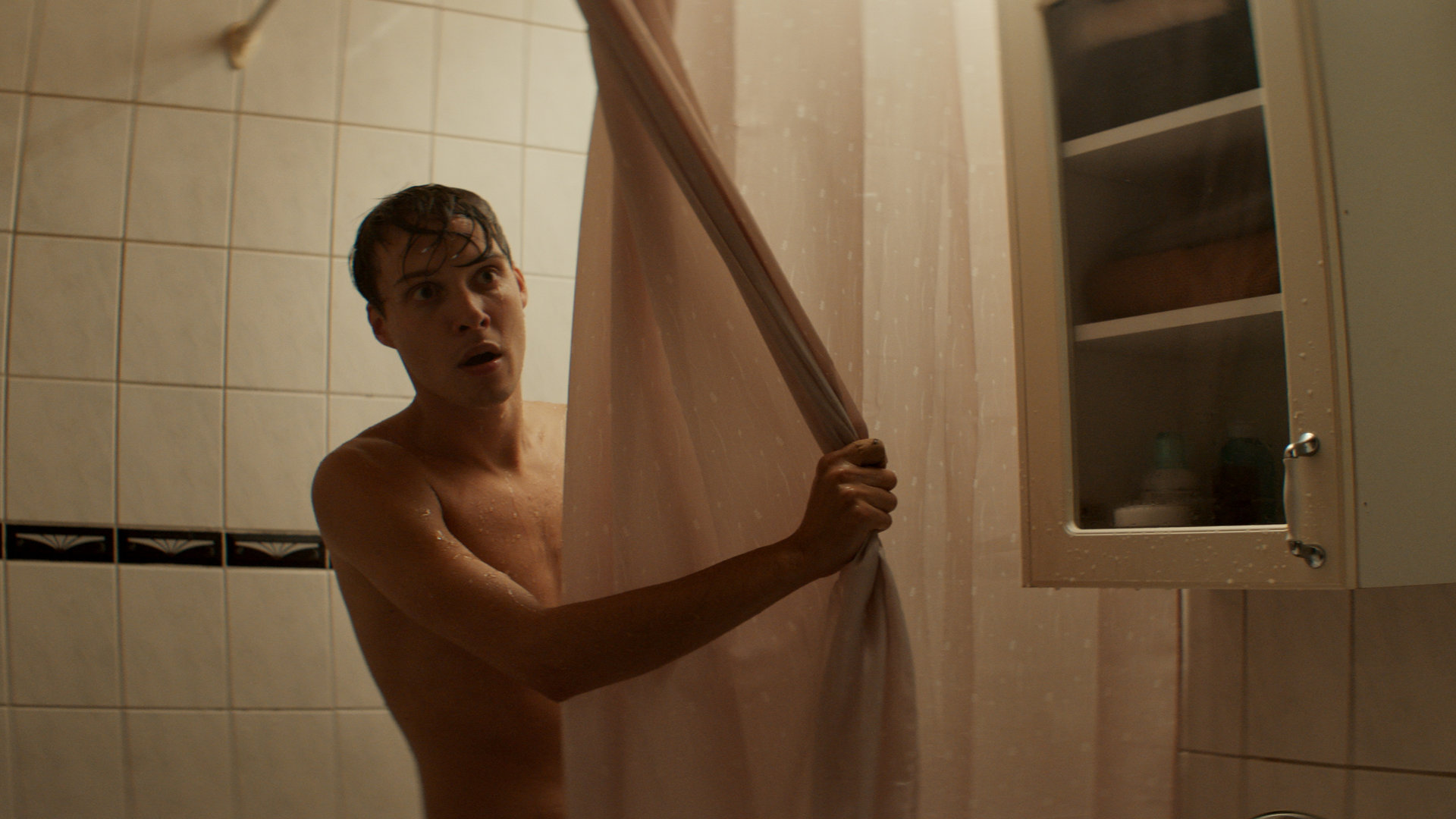 "Cryptid - Tuvas Begegnung": Niklas (Julius Fleischanderl) steht in der Dusche und schaut hinter dem Vorhang hervor.