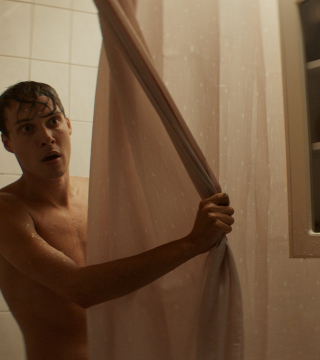 "Cryptid - Tuvas Begegnung": Niklas (Julius Fleischanderl) steht in der Dusche und schaut hinter dem Vorhang hervor.