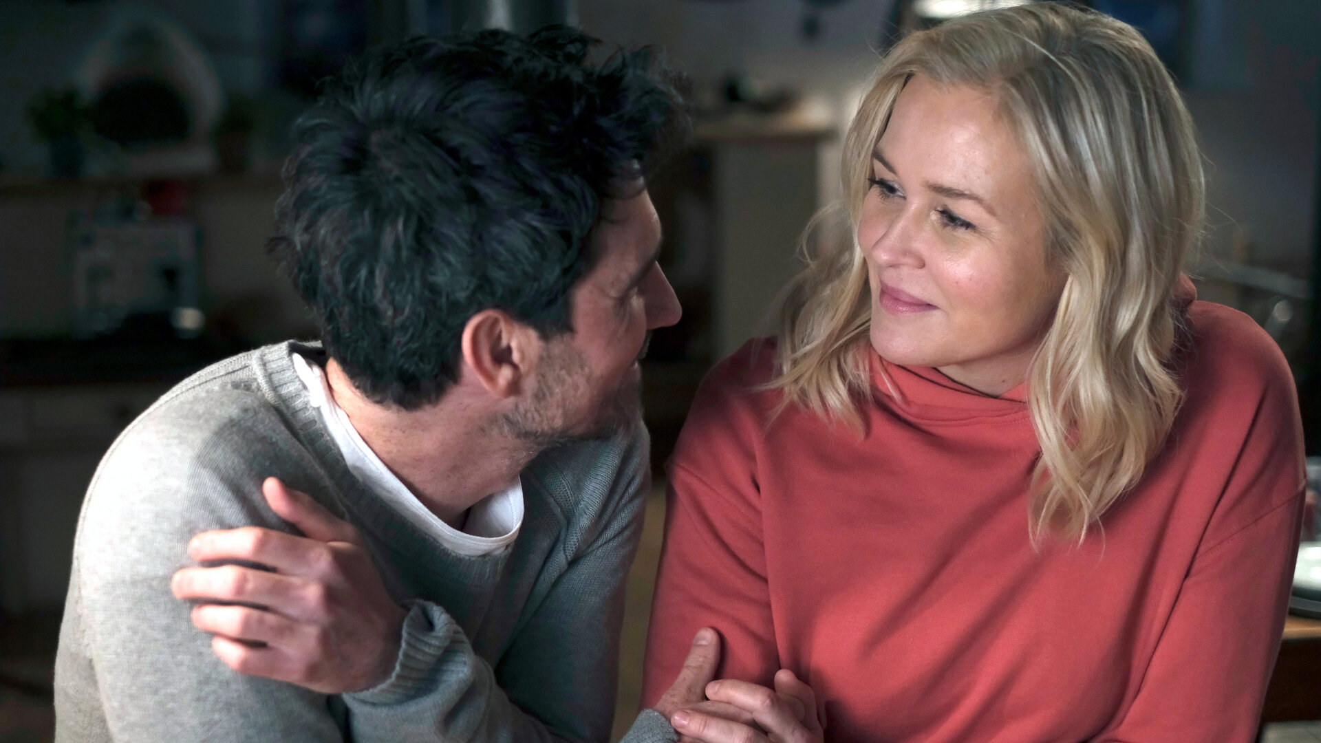 "Lena Lorenz - Benita und Muck": Nahaufnahme: Lena Lorenz (Judith Hoersch) und Rob Manzini (Seán McDonagh) sitzen dicht nebeneinander, halten sich an den Händen und lächeln sich zärtlich an.