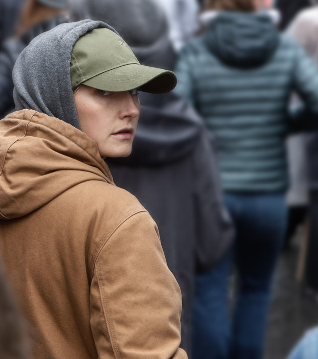 "Furia (2)": Mit Hoody und tiefsitzender Schildmütze bekleidet, läuft Ragna (Ine Marie Wilmann) inmitten einer Menschenmasse und blickt misstrauisch über ihre Schulter.