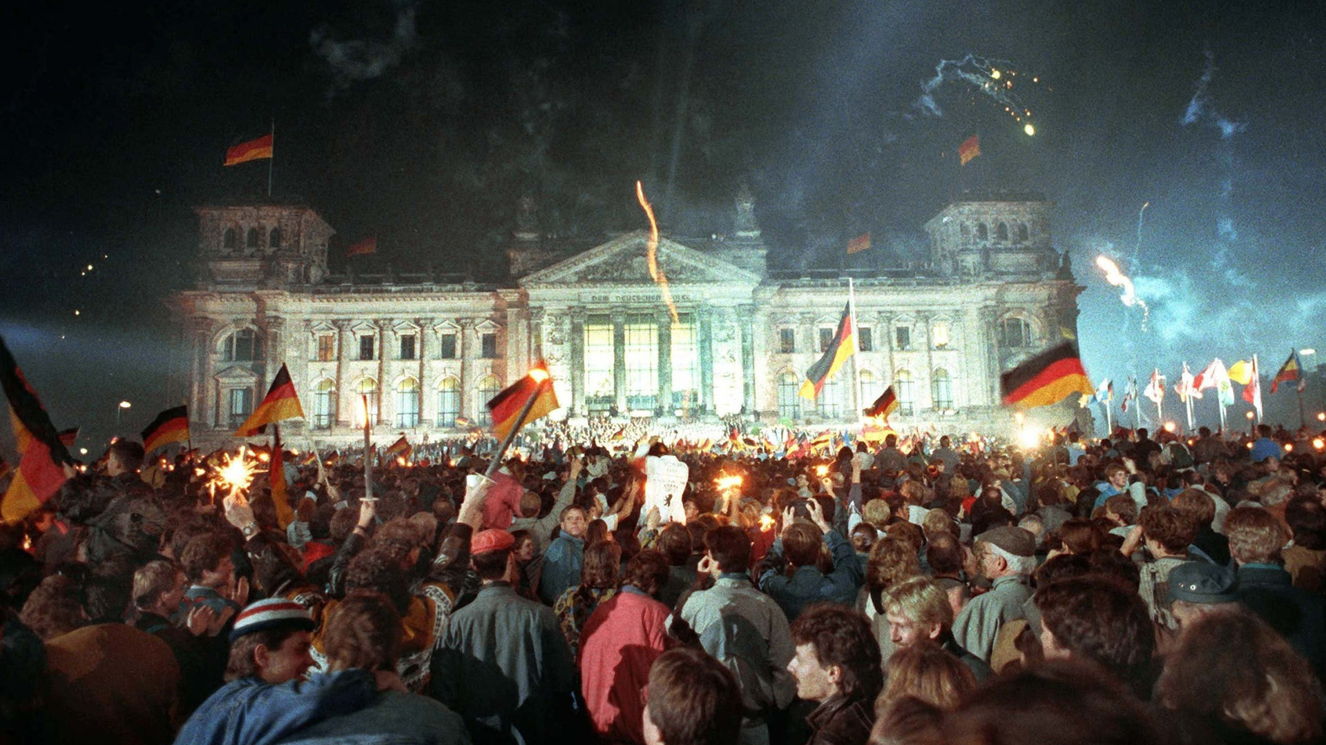 "Deutschland ''90 - Countdown zur Einheit": Menschenmassen vor dem Berliner Reichstag, die mit Feuerwerk, Deutschlandfahnen und Volksfesttrubel die wiedergewonnene Einheit Deutschlands feiern. Mit dem 3. Oktober 1990 sind die Deutschen 45 Jahre nach dem Ende des Zweiten Weltkrieges wieder in einem souveränen Staat vereint.