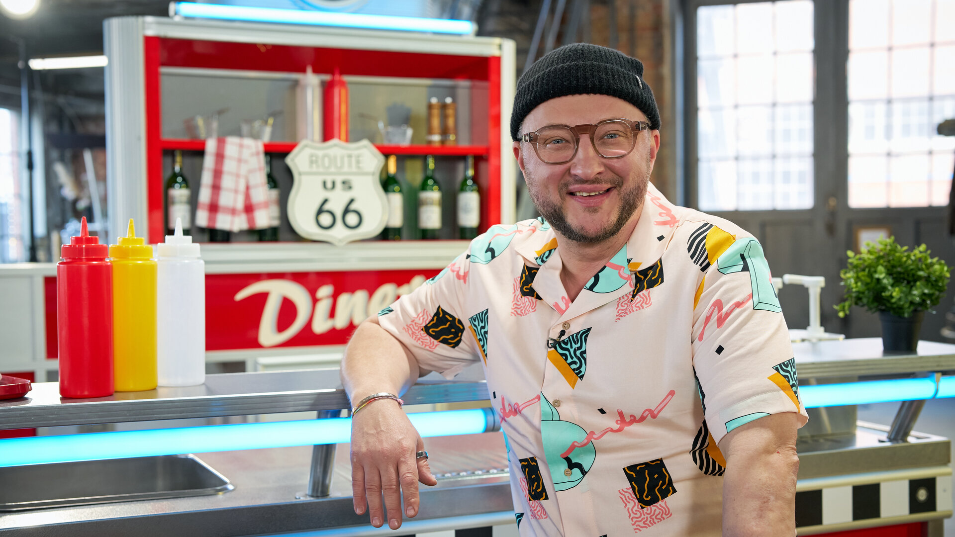 "besseresser: Die Tricks der Lebensmittelindustrie weltweit - Sebastian Lege deckt auf": Sebastian Lege sitzt im Studio an der Theke eines Diners.