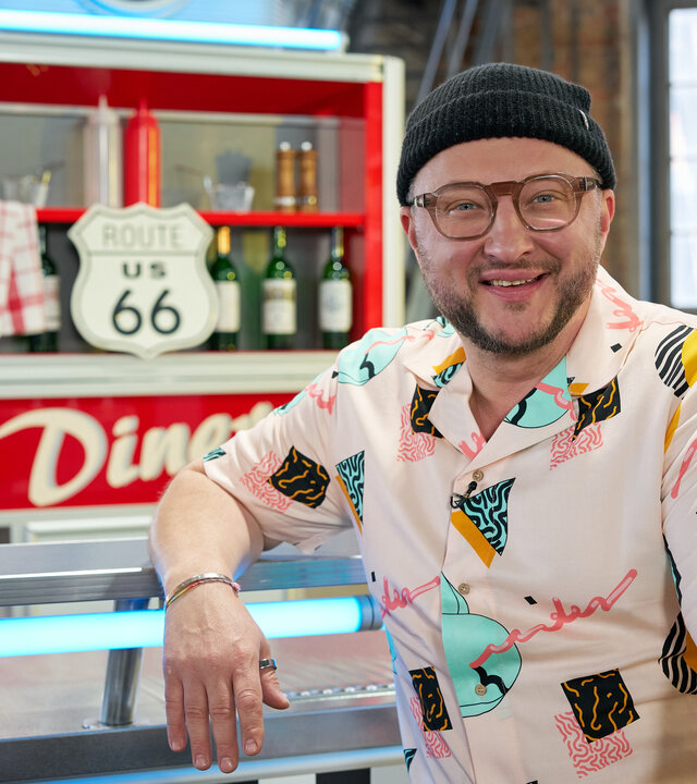 "besseresser: Die Tricks der Lebensmittelindustrie weltweit - Sebastian Lege deckt auf": Sebastian Lege sitzt im Studio an der Theke eines Diners.