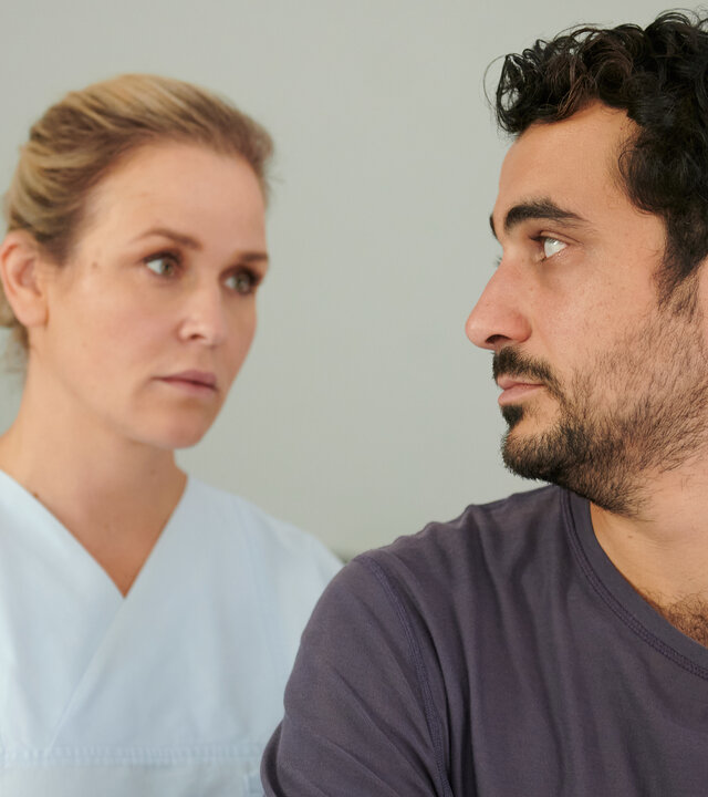 "Lena Lorenz - Schicksalsschlag": Ben Tewolde (Timo Fakhravar) schaut Lena Lorenz (Judith Hoersch) an, die in Klinikkleidung hinter ihm steht.