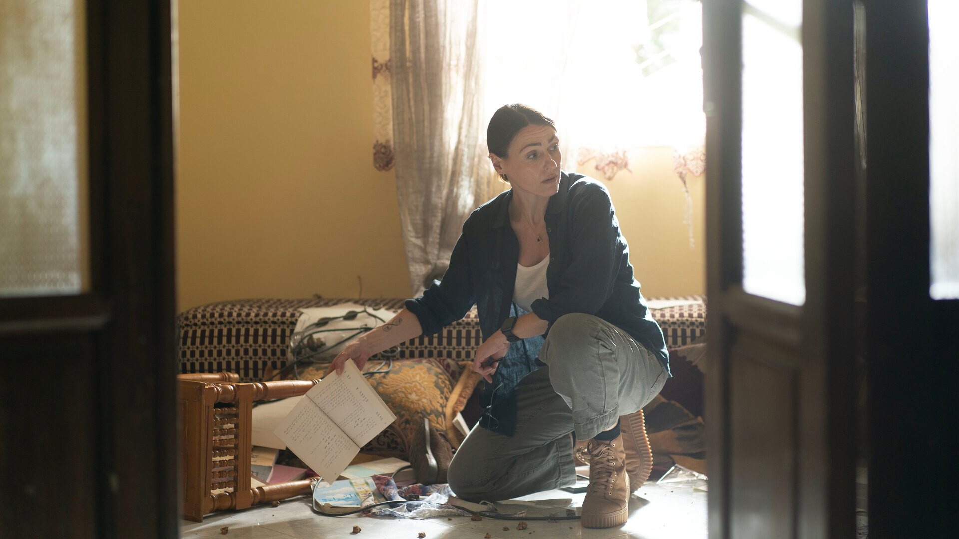 "Vigil - Tödliche Drohnen: Verdachtsmomente": DCI Amy Silva (Suranne Jones) kniet in einem verwüsteten Zimmer auf dem Boden und schaut sich um.