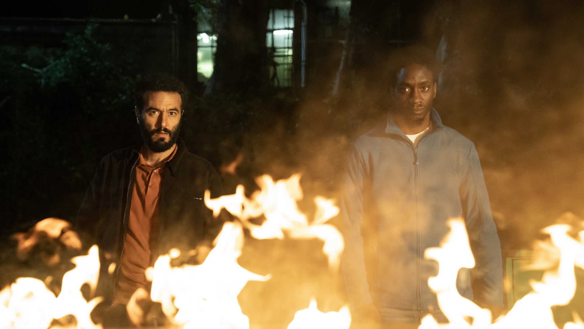 "LIBERAME - Nach dem Sturm - Leuchtfeuer": Akono Chuke (Emmanuel Ajayi) und Ismail Sabia (Mohamed Achour) stehen nebeneinander vor einem Feuer und schauen entschlossen in die Kamera.