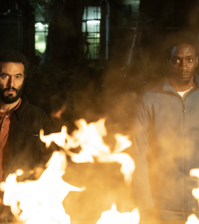 "LIBERAME - Nach dem Sturm - Leuchtfeuer": Akono Chuke (Emmanuel Ajayi) und Ismail Sabia (Mohamed Achour) stehen nebeneinander vor einem Feuer und schauen entschlossen in die Kamera.