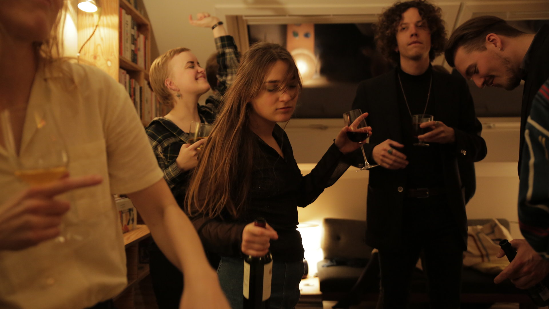 "About Saturday - Der Tag danach": Klara (Darin Hagi) tanzt inmitten einer Menge junger Leute auf einer Party und hält eine Flasche Wein in der Hand.