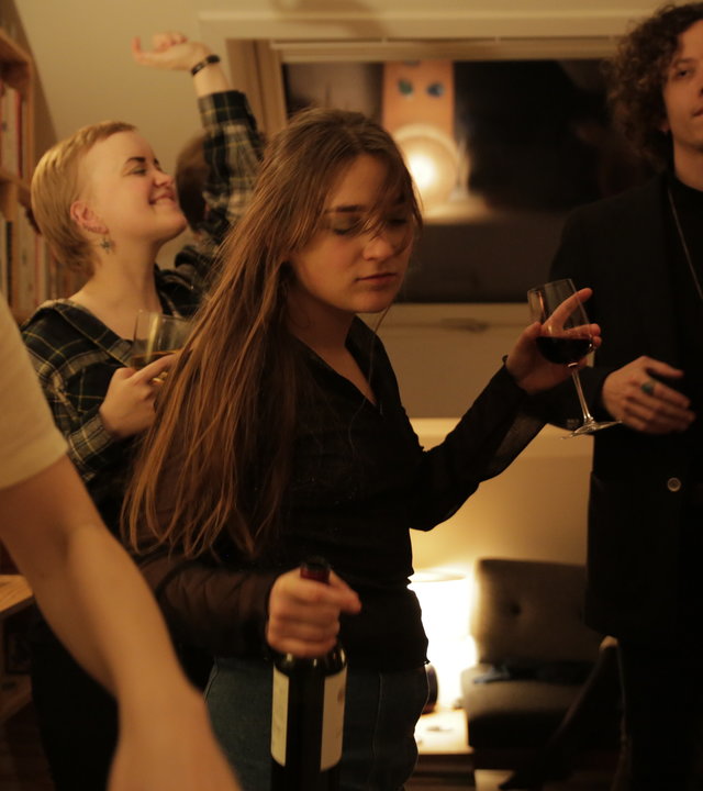 "About Saturday - Der Tag danach": Klara (Darin Hagi) tanzt inmitten einer Menge junger Leute auf einer Party und hält eine Flasche Wein in der Hand.