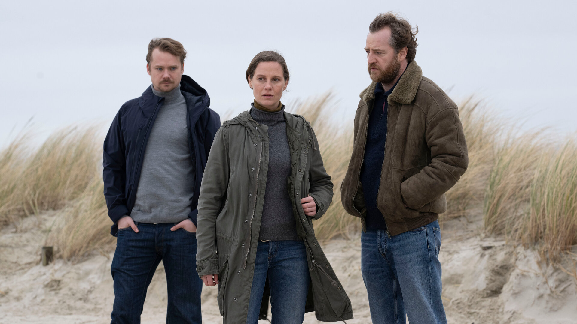 "Ostfriesentotenstille": Kommissarin Ann Kathrin Klaasen (Picco von Groote) steht zusammen mit ihrem Kollegen Frank Weller (Tom Radisch) und Dr. Bernhard Sommerfeldt (Sven Schelker) am Rande einer Düne. Jeder hat einen nachdenklichen und ernsten Blick.