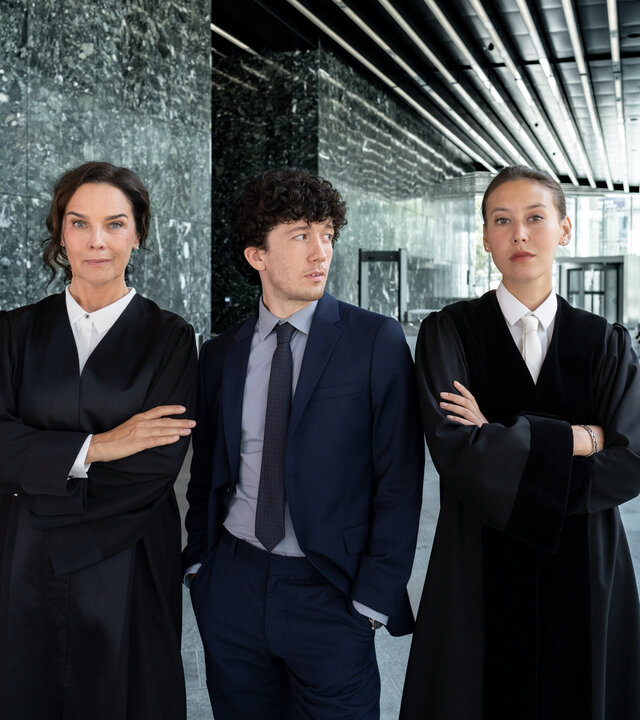 "Ein Fall für Conti - Spieler": Anna Conti (Désirée Nosbusch), Carlo von Hehenkamp (Maximilian Mundt) und Henry Mahn (Malaya Stern Takeda) stehen nebeneinander im großzügigen Foyer eines modernen Gebäudes.