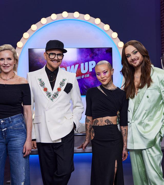 "Glow Up - Deutschlands nächster Make-up-Star - Social Media": Die Jurorin Loni Baur, Juror Armin Morbach, Gastjurorin Mei Pang und Moderator Riccardo Simonett posieren vor dem Jurytisch im "Glow-Up"-Studio.