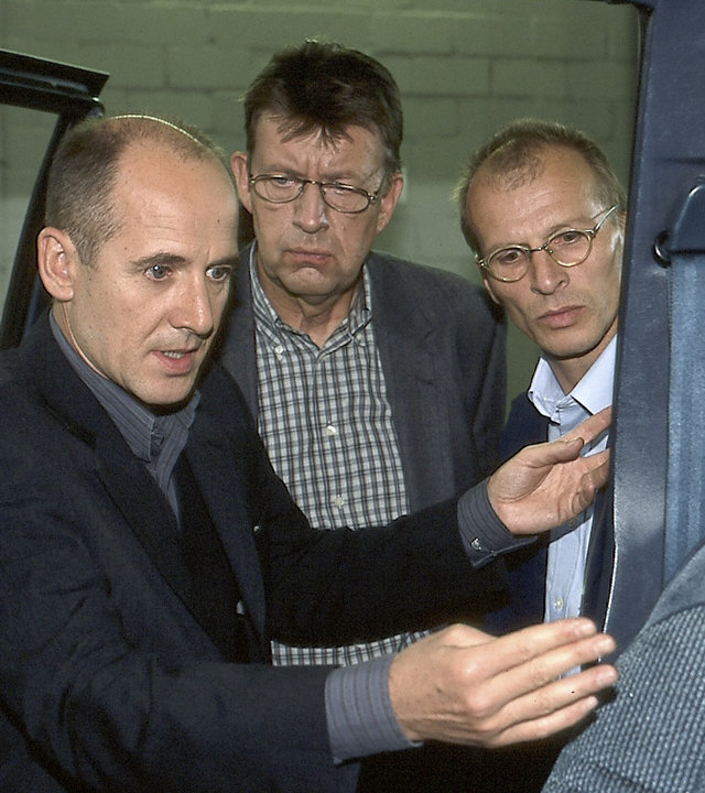 "Der letzte Zeuge - Im Netz": Dr. Robert Kolmaar (Ulrich Mühe), Joe Hoffer (Jörg Gudzuhn) und der Unfallsachverständiger Walter Erhardt (Jens-Uwe Bogadtke) stehen an einer Autotür und schauen alle drei ins Innere des Fahrzeugs.