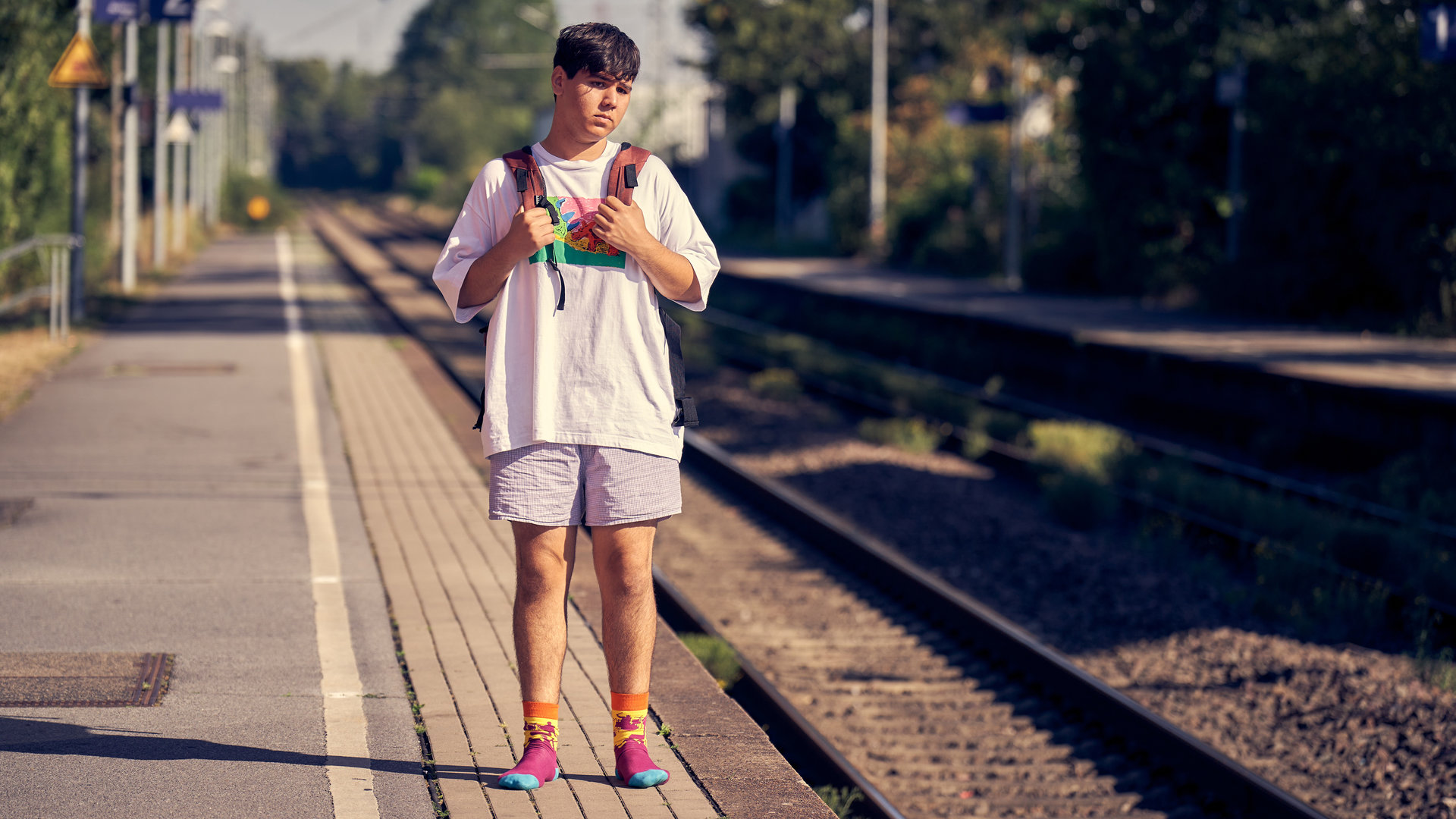 "Like a Loser - Der Ernst der Lage": Ernst (Diyar Ilhan) steht am Gleis 2 eines Bahnhofs und blickt wartend in die Ferne. Er trägt lediglich ein weißes T-Shirt, Boxershorts und Socken sowie einen Rucksack.