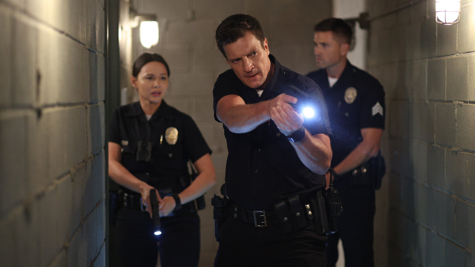 "The Rookie - Feuer und Flamme": Nolan (Nathan Fillion), Chen (Melissa O'Neil) und Bradford (Eric Winter) gehen mit der Waffe im Anschlag durch einen schmalen Gang.