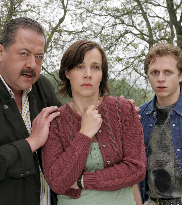 "Die Rosenheim-Cops - Gefährliche Nachbarn": Kommissar Korbinian Hofer (Joseph Hannesschläger) befragt Paula Wiesinger (Jutta Schmuttermaier) und deren Sohn Albi Wiesinger (Ferdinand Schmidt-Modrow) am Tatort. Im Hintergrund sind Bäume zu sehen.