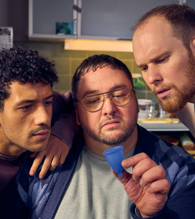 "Ich dich auch! - Die Tasse": Yannik (Rojan Juan Barani), Sven (Sven Daniel Bühler) und Tüffi (Daniel Zillmann) schauen skeptisch auf ein blaues Gummitütchen, das Tüffi hochhält.
