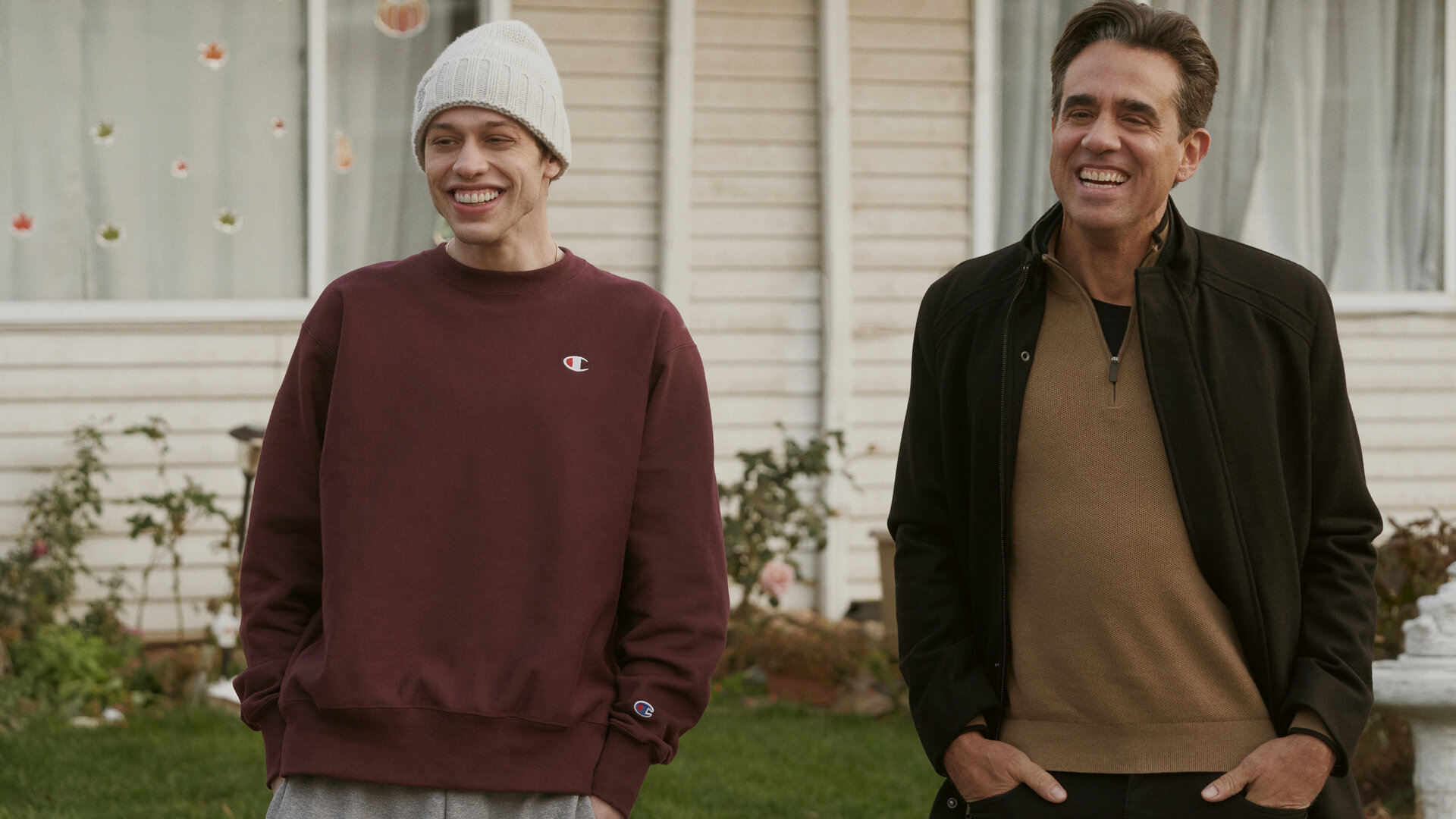 "Bupkis - Tu was ich sage, nicht was ich tue": Pete (Pete Davidson) steht lässig, mit den Händen in den Hosentaschen im Vorgarten von Onkel Tommy (Bobby Cannavale). Auch Onkel Tommy steht mit den Händen in den Taschen und lacht wie Pete.