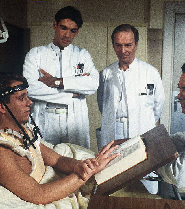 "Die Schwarzwaldklinik - Die Freundin": Tobias (Sven Jürgen Hasper) liegt im Krankenbett. Neben ihm am Bett stehen Dr. Udo Brinkmann (Sascha Hehn), Dr. Römer (Horst Naumann) und Prof. Brinkmann (Klausjürgen Wussow).