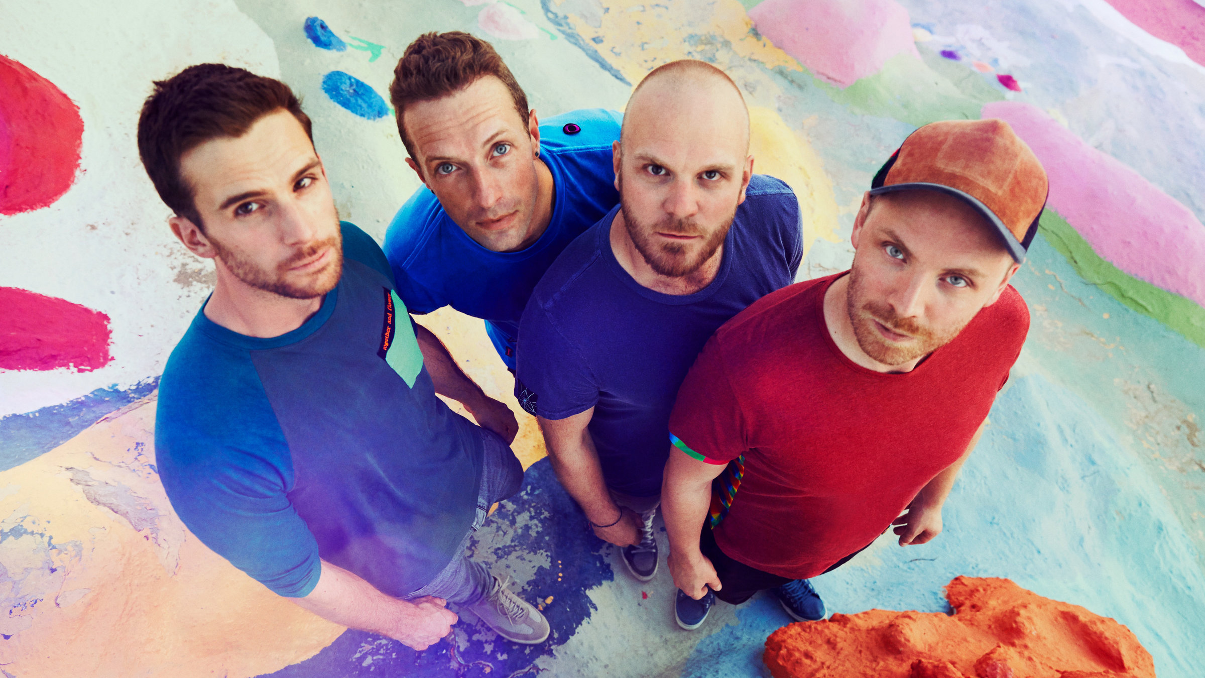 "Coldplay: Live in São Paulo": Die vier Männer der Gruppe Coldplay stehen auf einem bunten Untergrund, alle schauen hoch in die Kamera, die von oben fotografiert