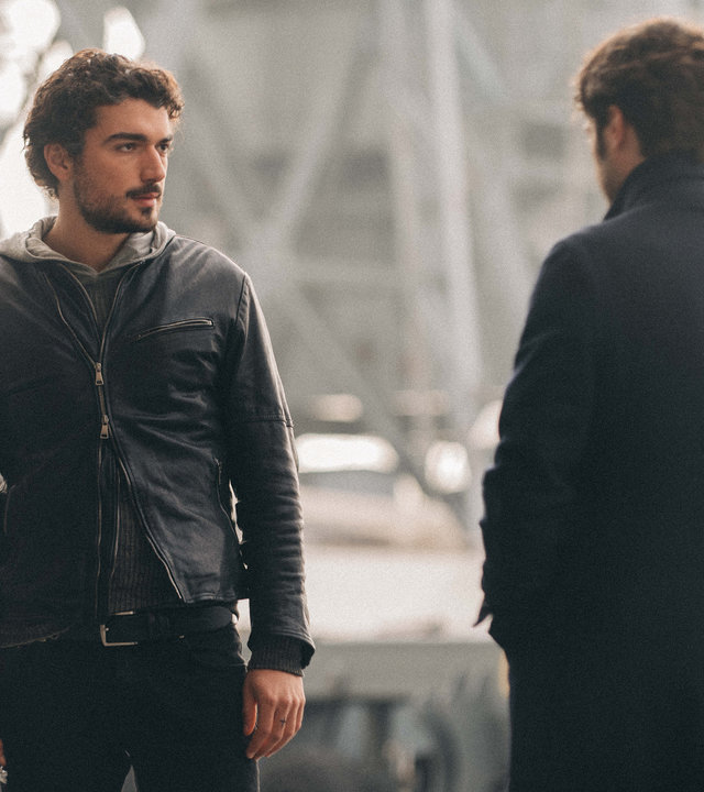 "Survivors - Vermutungen": Lorenzo (Giacomo Giorgio) steht Luca (Lino Guanciale) im Außenbereich der Werft gegenüber. Lorenzo blickt Luca vielsagend an.