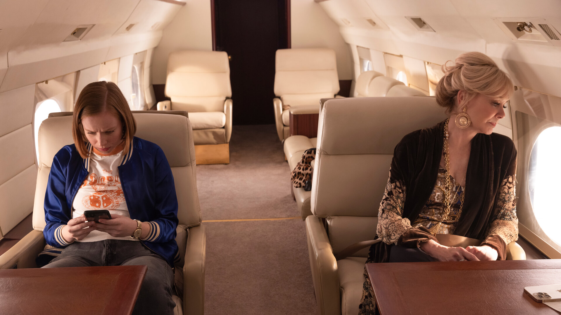 "Hacks - Blut wird fließen": Ava (Hannah Einbinder) und Deborah (Jean Smart) sitzen in einer luxuriösen Flugzeugkabine. Während Ava vertieft auf ihr Handy schaut, richtet Deborah ihren Blick nachdenklich aus dem Fenster des Flugzeugs.