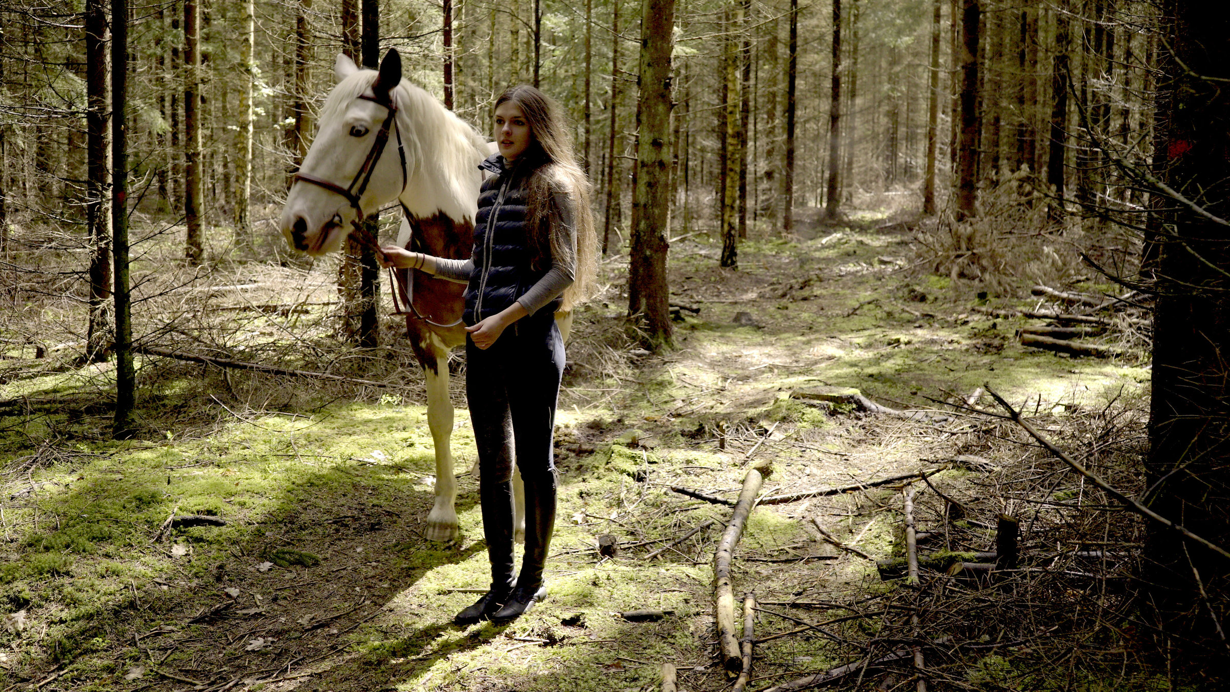"Ab 18 - Ewas Brief": Junges Mädchen mit Pferd im Wald in der Totalen.