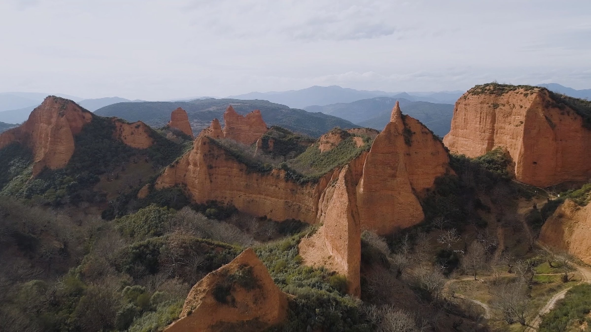 "Südspanien von oben": Rötliche Felswände und -spitzen ragen aus grünen Hängen auf.