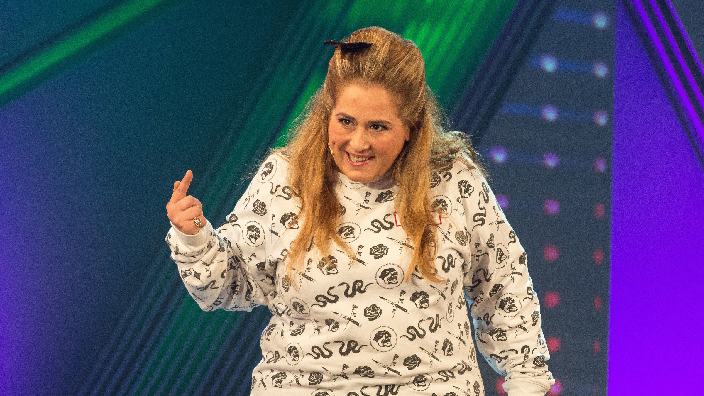 "Idil Baydar als Jilet Ayse: Deutschland, wir müssen reden!": Idil Baydar mit gemustertem beigen Pulli und schwarzer Hose auf der Bühne.