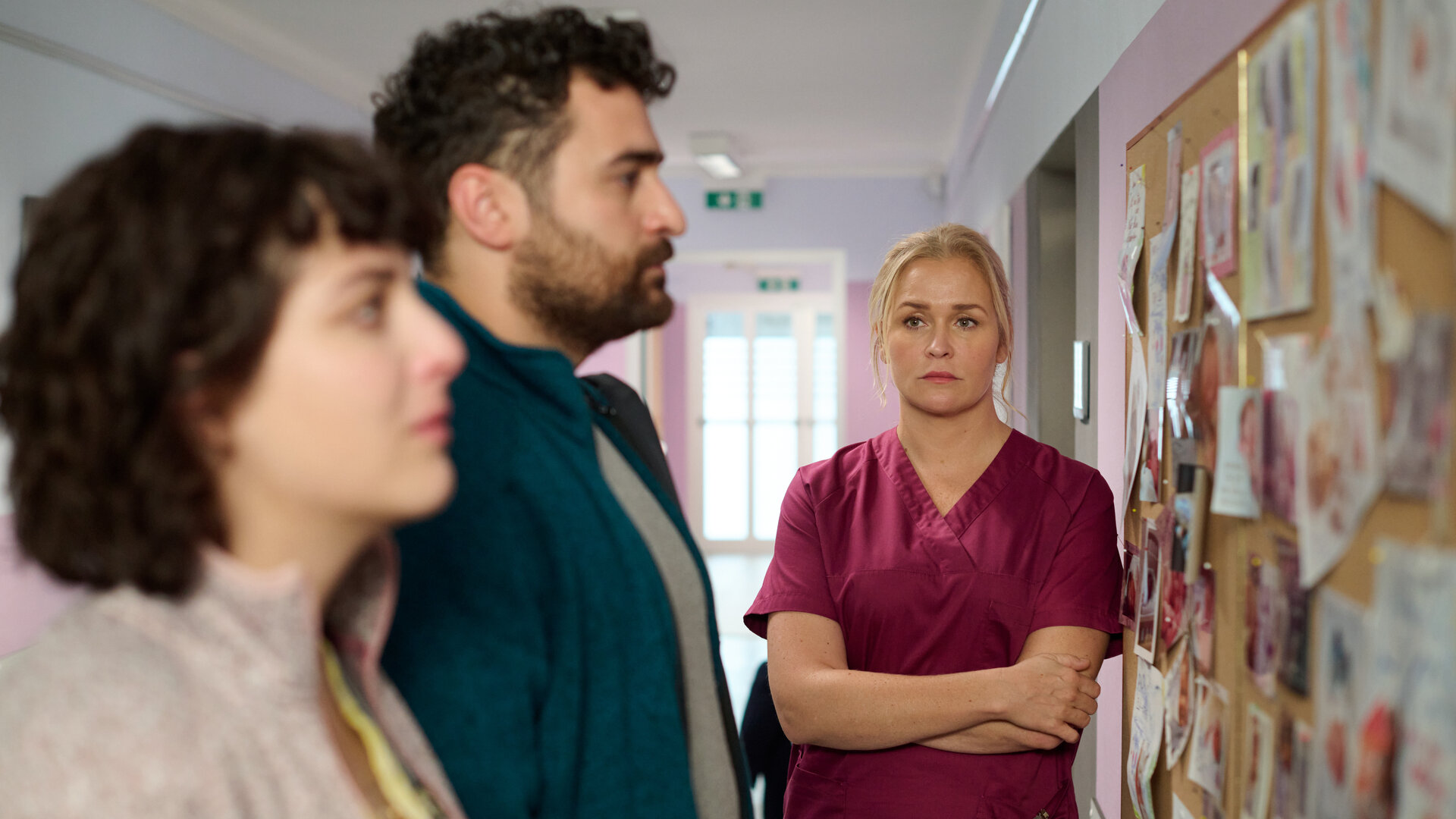 "Lena Lorenz - Das Leben ist jetzt": In einem Krankenhausflur stehen Ina (Anna Werner Friedmann) und Felipe Fromme (Ugur Kaya) vor einer Pinwand mit Babyfotos, die sie mit verzweifeltem Gesichtsausdruck betrachten. Lena Lorenz (Judith Hoersch) steht mit verschränkten Armen daneben und schaut das Paar traurig an.