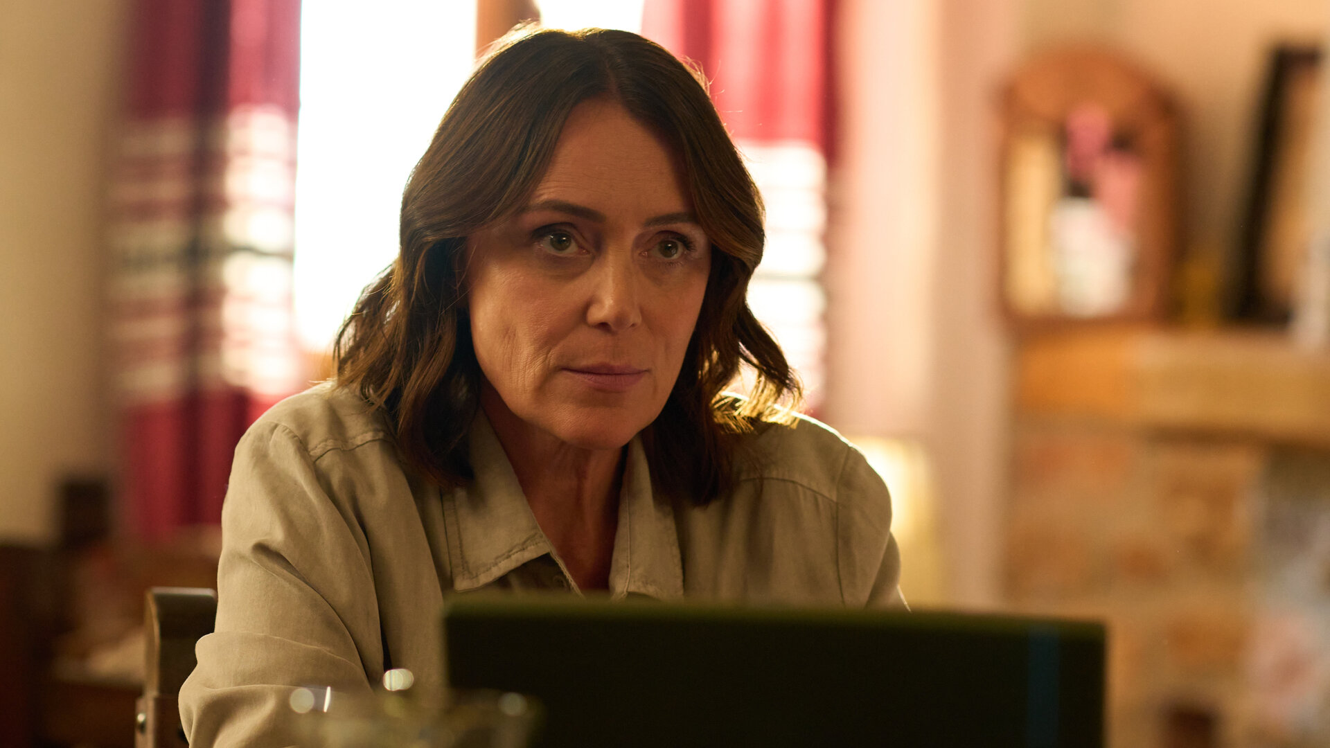 "The Assassin - Ein kotzgrüner Laptop": Julie (Keeley Hawes) sitzt in einem Wohnraum vor einem aufgeklappten Laptop.