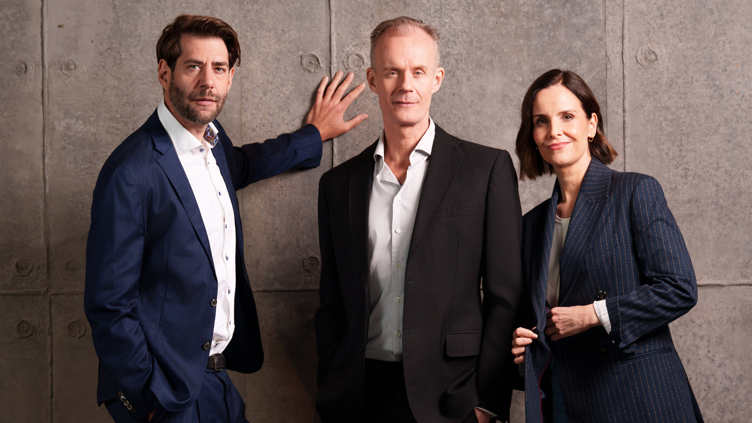 "Die Anstalt": Claus von Wagner, Max Uthoff und Maike Kühl stehen vor der Betonwand des Bühnenbildes und schauen in die Kamera.