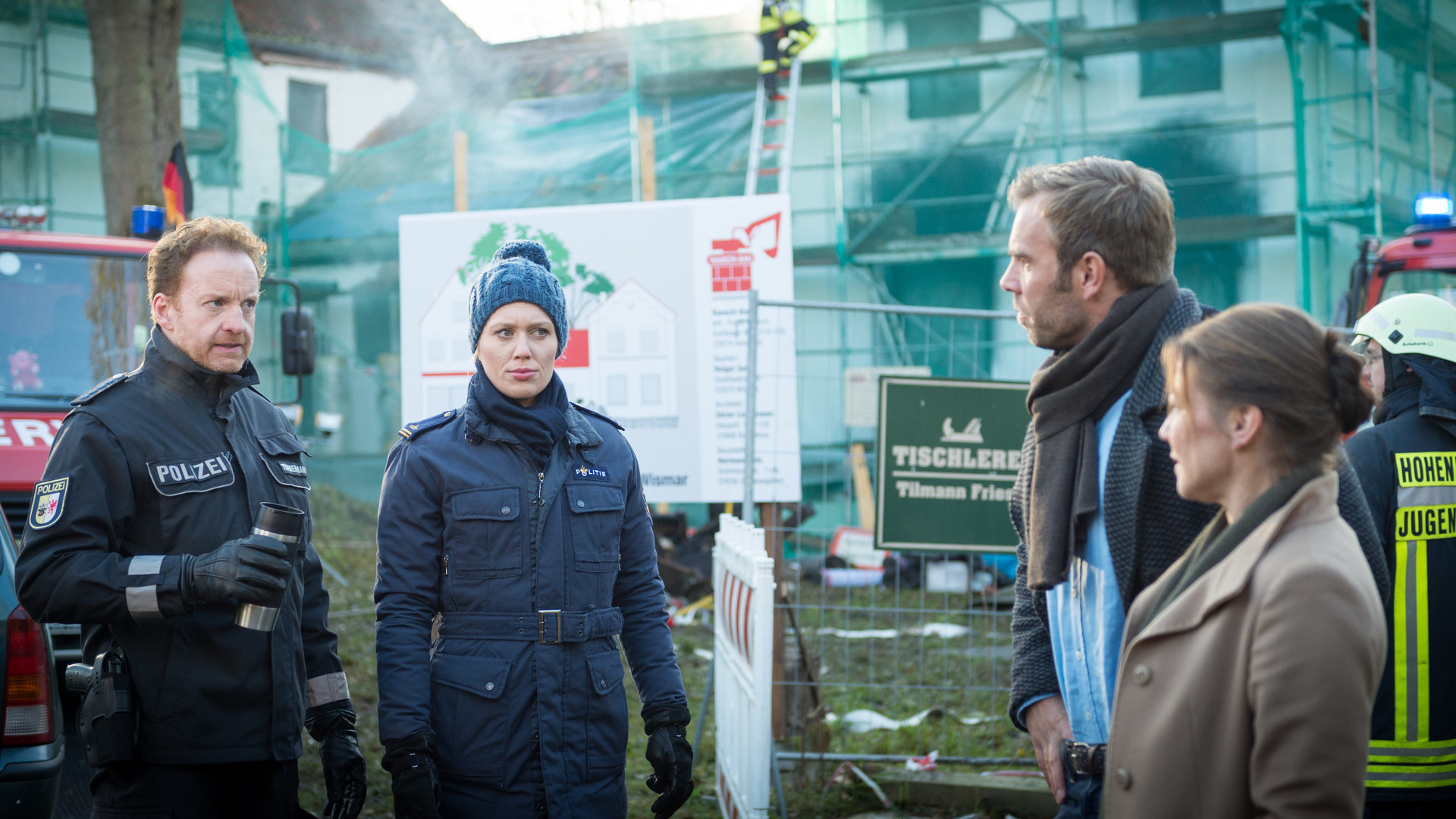 „SOKO Wismar – Tödlich frisch“: Katrin Börensen (Claudia Schmutzler), Lars Pöhlmann (Dominic Boeer), Anneke van der Meer (Isabel Berghout) und Timmermann (Mathias Junge) stehen nebeneinander. Im Hintergrund sind Einsatzwagen der Feuerwehr sowie die Brandstelle zu sehen.