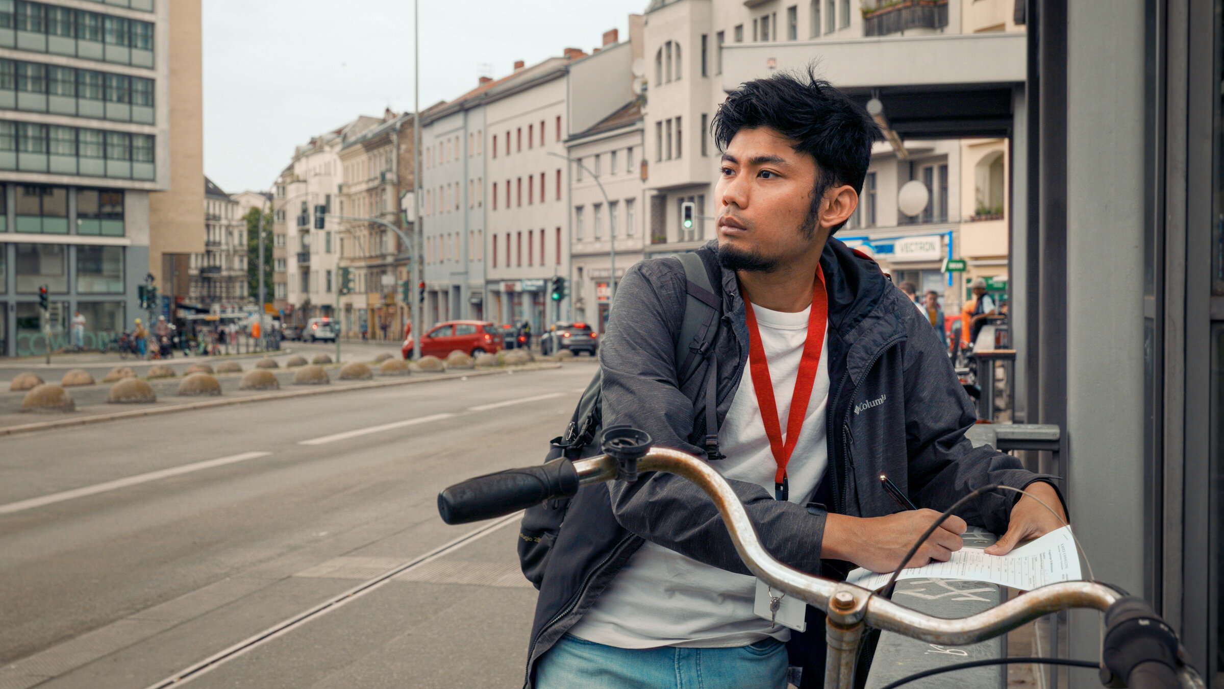 "Ab 18! - Großstadt Odysseus": Junger Mann steht an einem Geländer und macht sich auf einem Blatt Papier Notizen.
