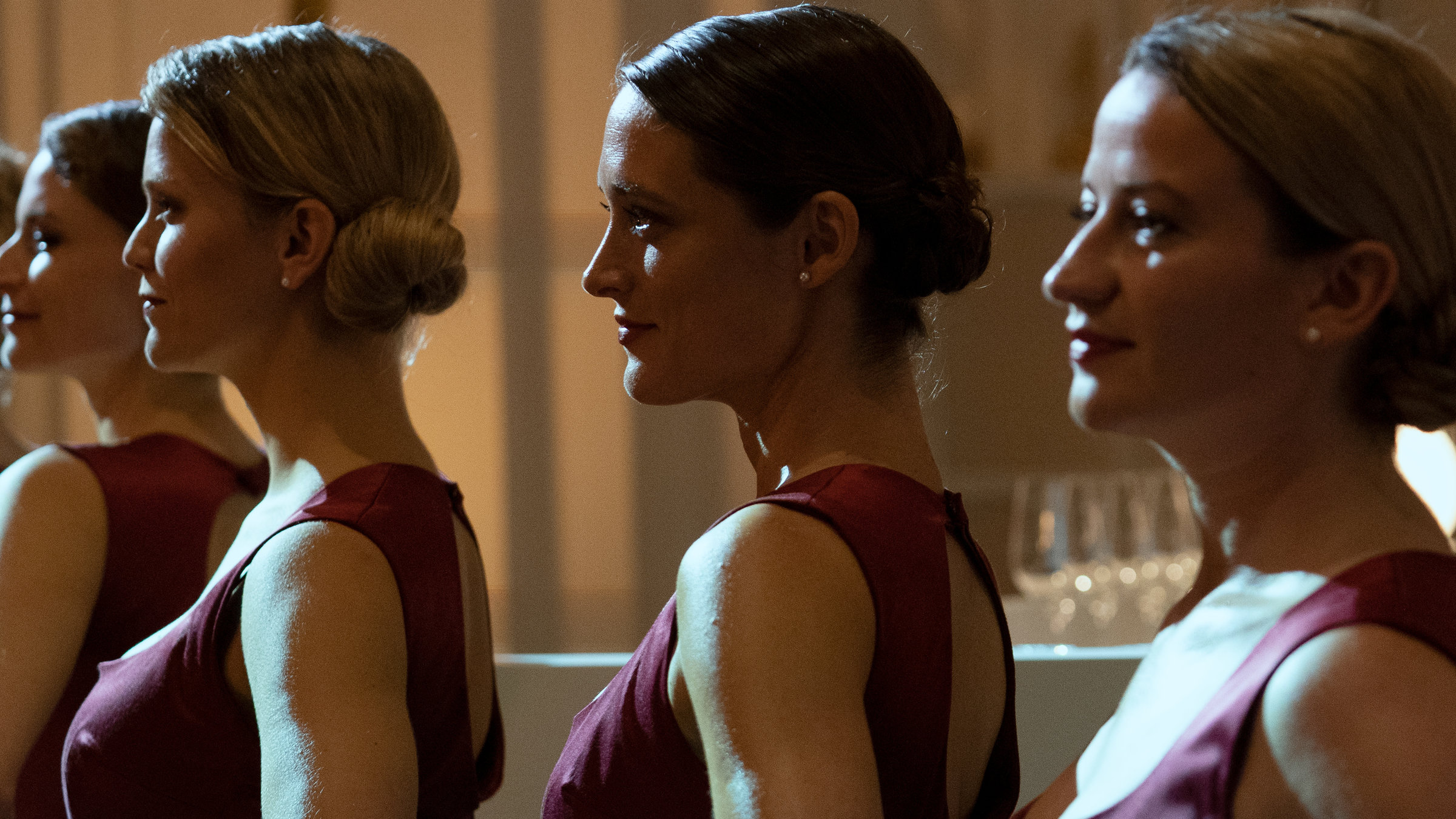 "So laut du kannst": Vier Gastro-Hostessen, darunter Kim (Friederike Becht) und Maja (Nina Gummich) in roten Cocktail-Kleidern stehen hintereinander aufgereiht.