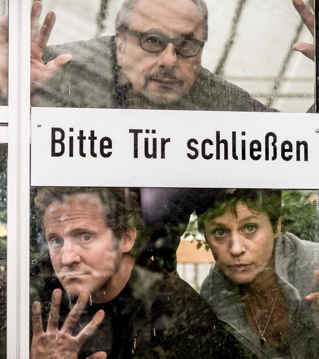 "Die Insassen": Löhring (Wolfgang Stumph), Winter (Maximilian Brückner) und Karin Schlick (Jule Ronstedt, hinter der Tür eines Glasgewächshauses, auf der steht "Bitte Tür schließen".